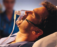 Man sleeping in bed with oxygen mask on his face.