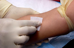 Image of a trained technician swabbing the arm of a patient with alcohol.